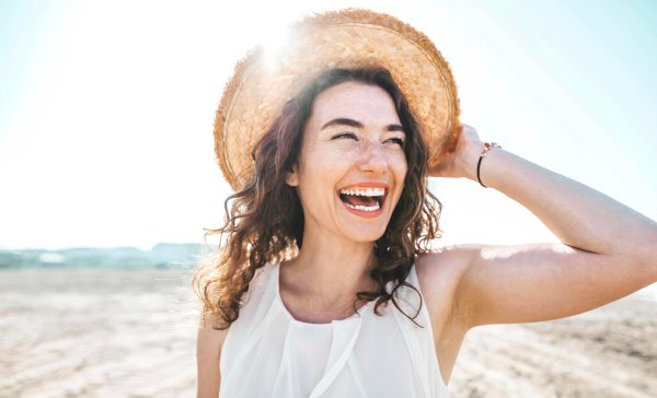 young freckled woman wearing straw hat at the beach