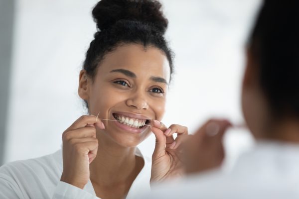 beautiful woman flosses teeth in mirror