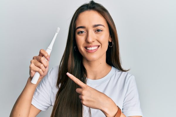 brunette holds electric toothbrush